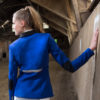 Junge Frau mit Reitsakko in Royalblau und Reißverschlüssen in einer Reithalle