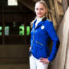 Junge Frau mit Reitsakko in Royalblau und Reißverschlüssen in einer Reithalle