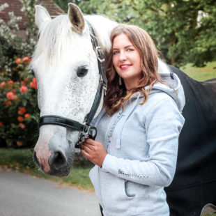 Lachende Frau mit Pferd in einem Hellgrauem Kapuzenpullover